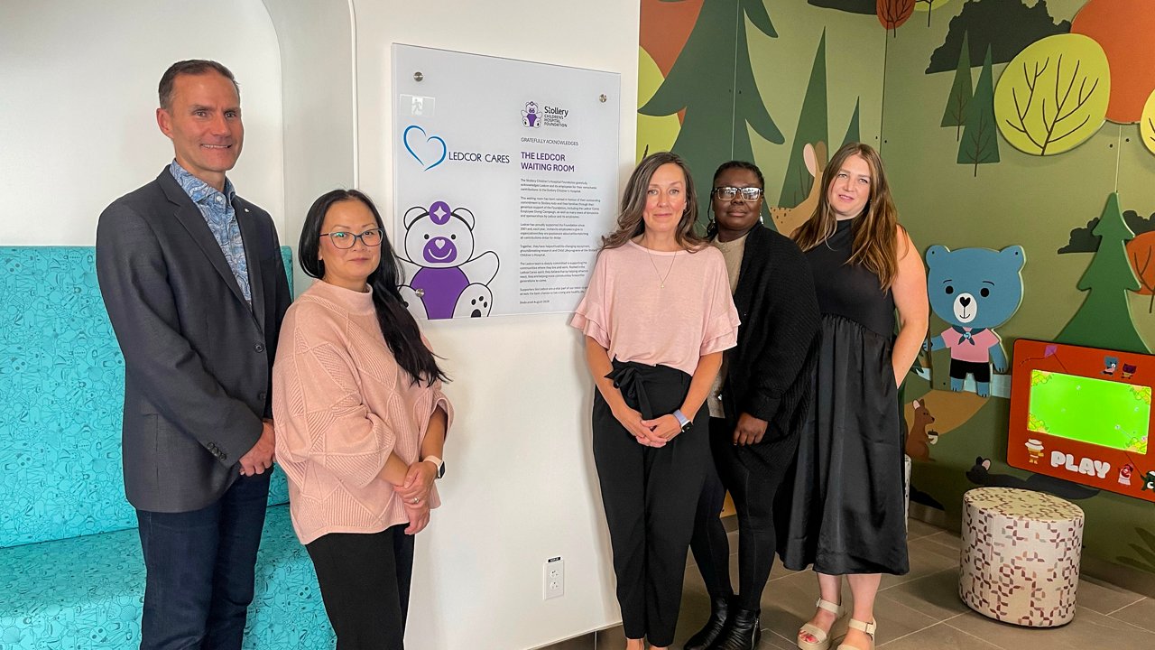 A group of Ledcor and Stollery Hospital personnel standing in front of a commemorative plaque